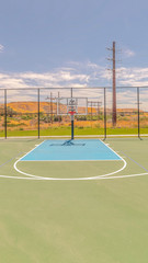 Vertical Outdoor basketball court on sunny, blue day