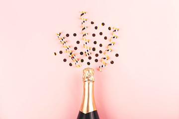 Creative New Year composition with champagne bottle and exploding gold confetti and streamers....