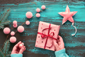 Female hands wrapping Xmas gift, winter decorations and fir twigs. Christmas flat lay in blue,...