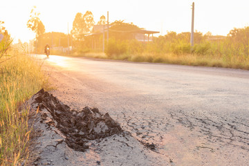The side of the paved road was broken with early orange light.