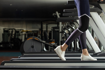 Fototapeta na wymiar Legs White Shoes of slim Fitness woman exercise warm up on running machine treadmill in Fit Gym. Concept female Can Do athlete Sport healthy, copy space