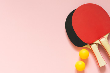 Black and red tennis ping pong rackets and orange balls isolated on a pink background, sport equipment for table tennis