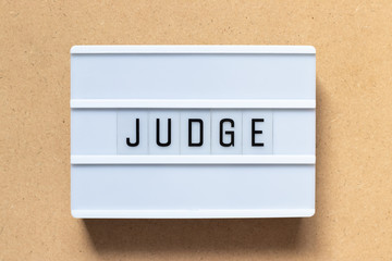 White lightbox with word judge on wood background