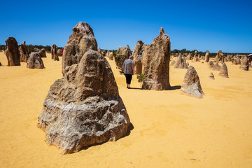 Fototapeta na wymiar Landscape view of mature woman tourist admiring the limestone pinnacles in the Nambung National Park, Cervantes, Western Australia.