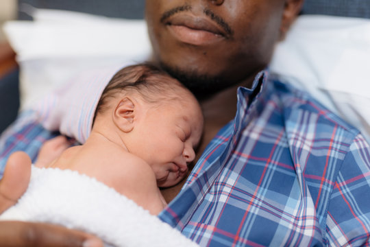 african american father holding newborn baby in hospital