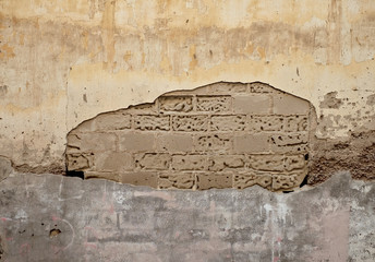 Vintage pastel colored wall with plaster exposing an old sand brick and mortar texture.