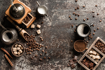Coffee cup with coffee grinder and coffee beans on dark textured background.