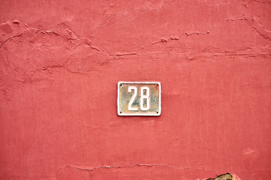 Number 28, twenty-eight, on a burgundy wall surface.