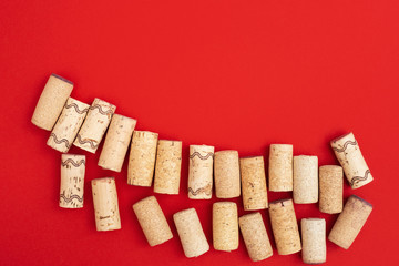 Wine corks on red paper background with copy space. Close up used wooden stoppers. Concept for red wine.