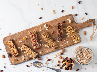 Granola bar with copy space. Set of different granola bars on cutting board over white marble table. Shallow DOF. Top view or flat lay.
