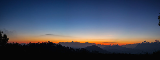 Sunset or sunrise mountain peaks colorful sky panorama.