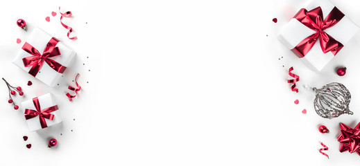 Christmas gift boxes with red ribbon, sparkles, confetti and decoration on white background. Xmas and Happy New Year holiday. Flat lay, top view