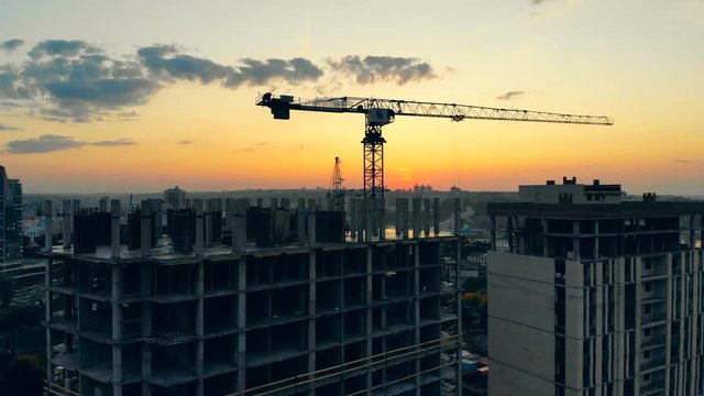 Building site with working blue crane on sunset background.