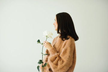 Smiling pretty woman wearing cashmere beige sweater holding a white rose © Anastasia Gosteva