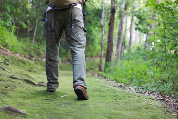 Hiking man with boots walking on the forest passage trail