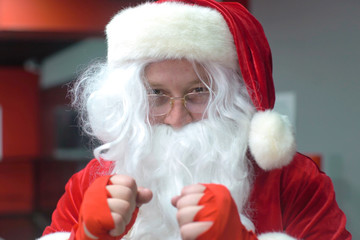 Santa Claus Fighter kickbox With Red Bandages boxer hitting a huge punching bag at a boxing studio. Santa Claus boxer training hard.