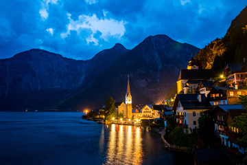 Scenic view of famous Hallstatt lakeside town reflecting in Hallstattersee lake in the Austrian Alps night time in summer, Salzkammergut region, Austria