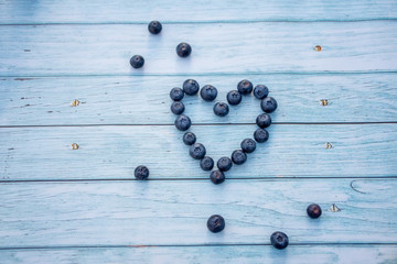 Superfood berries: blueberry heart on a wooden background.