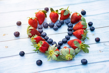 Naklejka na ściany i meble Blueberry and strawberry heart on a wooden background. Valentines day concept