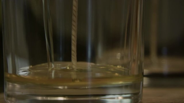 Extreme slow motion close up of wax being poured into an empty candle glass.