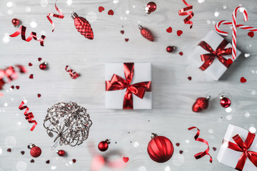 Merry Christmas card made of flying decorations, gift boxes, fir branches, red decoration, balls, sparkles and confetti on wooden background. Xmas and New Year holiday, bokeh, light. Selective focus
