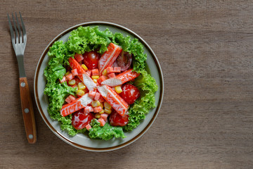top view of crab stick salad in a ceramic dish on wooden table. homemade style healthy food concept.