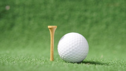 Golf ball and a tee on green grass