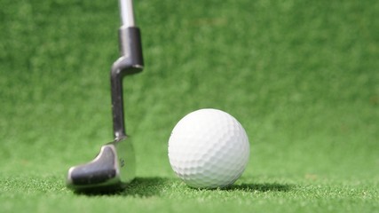 Golf putter and golf ball on green grass