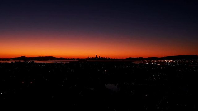 A fast time lapse of the sunset behind the urban city and the traffic below.