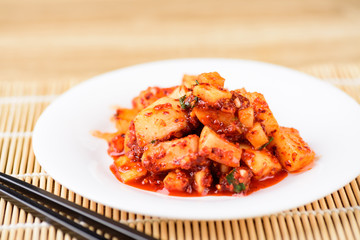Kimchi radish on white plate with chopsticks, Korean food