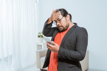 portrait of disapointed businessman receiving text message on his smartphone