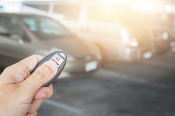 Hand holding car key remote at car park