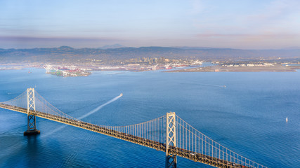 Sunset view of San Francisco Bay and the Bay Bridge; Oakland and the smoke plume from Kincade fire visible in the background; San Francisco, California