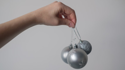 New Year's toys balls of silver color in a female hand on a light background. Christmas and new year concept. Christmas tree decoration