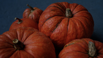 Orange pumpkins close-up, top view, selective focus. Template fall harvest thanksgiving halloween anniversary invitation cards. Dark background, photo in dark processing
