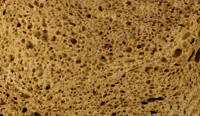 Texture of rye bread. A dark brown piece of bread. Close up