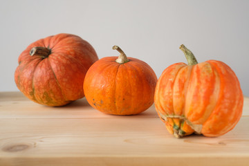 Halloween and Thanksgiving. Autumn concept. 3 orange pumpkins of different sizes on a wooden table. Autumn background. side view. Fall season.