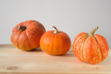 Halloween and Thanksgiving. Autumn concept. 3 orange pumpkins of different sizes on a wooden table. Autumn background. side view. Fall season.