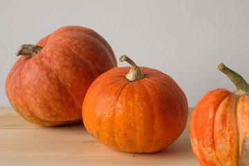 Halloween and Thanksgiving. Autumn concept. 3 orange pumpkins of different sizes on a wooden table. Autumn background. side view. Fall season.