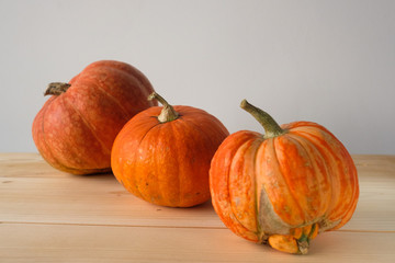 Halloween and Thanksgiving. Autumn concept. 3 orange pumpkins of different sizes on a wooden table. Autumn background. side view. Fall season.