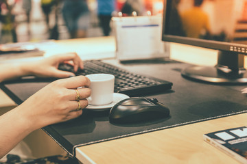 Woman hand holdding coffee cup with working table