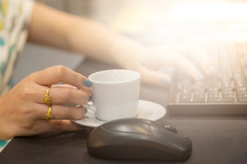 Fototapeta na wymiar Woman hand holdding coffee cup with working table