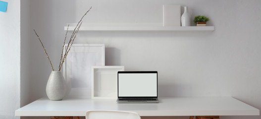 Loft style workplace with open blank screen laptop computer and mock up frame