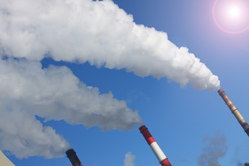 White smoke comes from pipes against blue sky