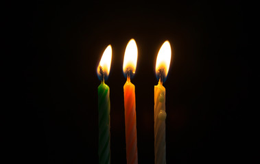 Green white pink birthday candle yellow lights burning in the dark and black background