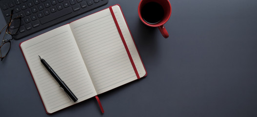 Top view of dark modern workplace with open notebook and red coffee cup - Powered by Adobe