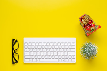 Merry Christmas and Happy new years office work space desktop shopping concept. Flat lay top view with keyboard, mini shopping cart and Christmas ornaments with copy space.