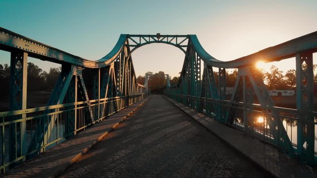 walking on a green, metal bridge at sunrise in Poland