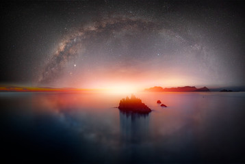 The milky way galaxy over the sea and  silhouette of rock in the night sky