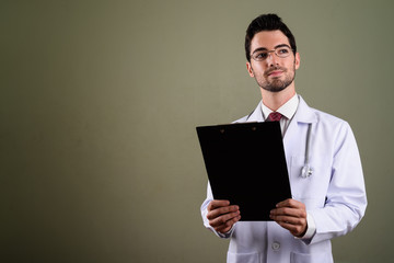 Portrait of young handsome man doctor with eyeglasses holding clipboard